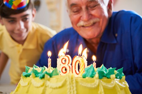 Esperanza de vida señor mayor soplando las velas de su 80 cumpleaños