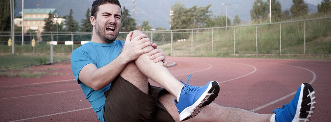 lesiones-en-el-triatlón hombre deportista con gesto de dolor agarrándose la rodilla