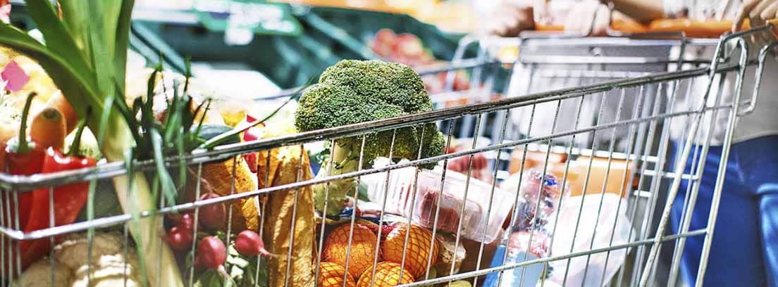 productos sanos supermercado Consejos para hacer una compra saludable: mujer con un carrito de compra en supermercado lleno de verdura y frutas