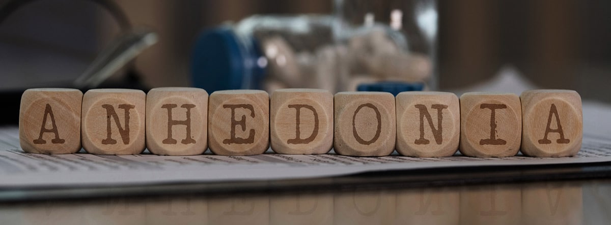 anhedonia ¿Qué es la anhedonia o falta de placer?: palabra anhedonia en cubos de madera