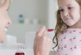 Uso correcto de medicamentos en niños: niña tomando una cucharada de jarabe