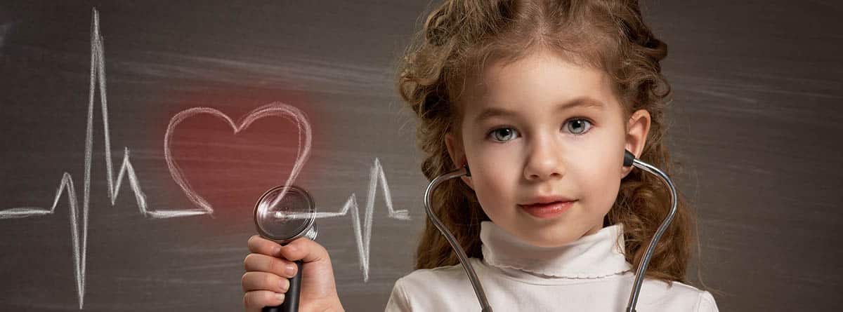 niña dibujando en la pizarra un corazón con latido