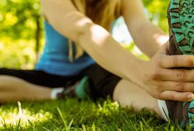 Mujer joven estirando en el parque