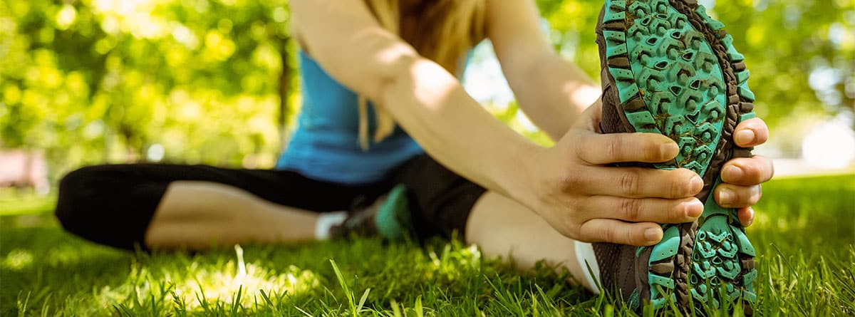 Mujer joven estirando en el parque