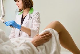 Mujer en consulta ginecológica con la especialista sujetando un aparato de láser