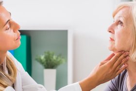 Mujer siendo revisada por una doctora, que le pone las manos en la garganta