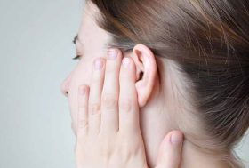 Mujer sujetándose la oreja de dolor
