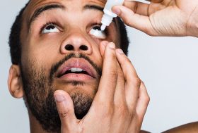 Hombre echándose colirio ojos