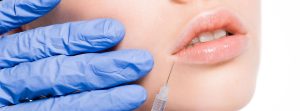 Labios de mujer y una mano con guante quirúrgico inyectándose